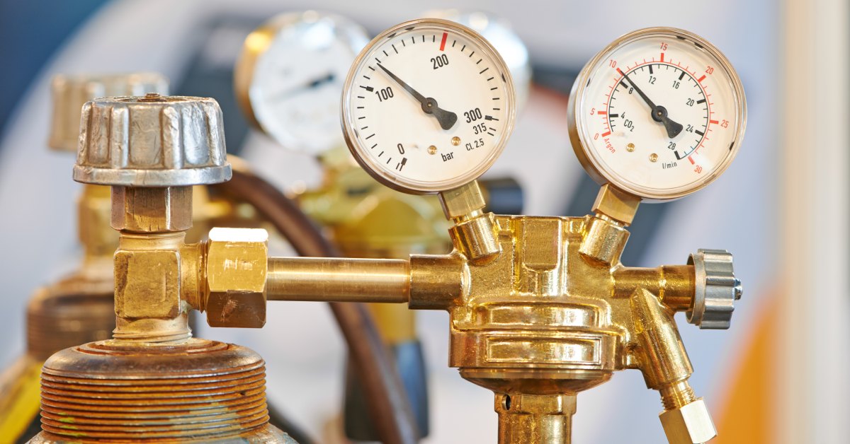 Two welding gas cylinder tanks stand side by side, with their gauges displaying the pressure of the gas inside.