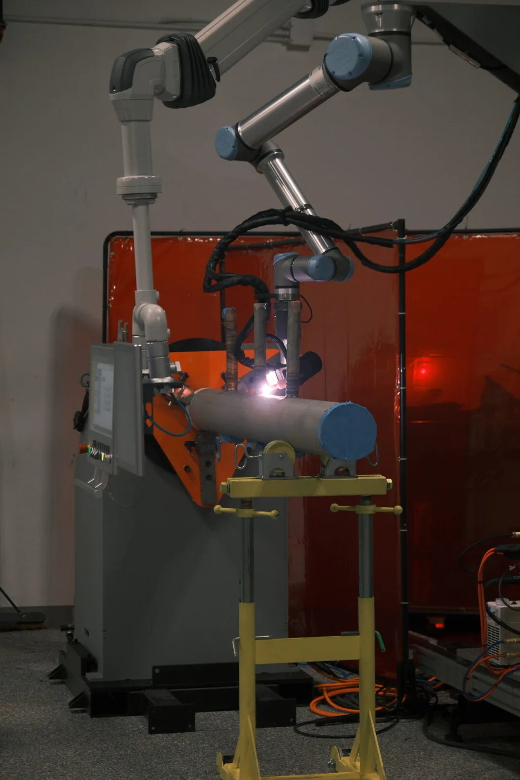 AutonoWeld M4 cobot torch laying an automated weld on a pipe spool with the arc lit