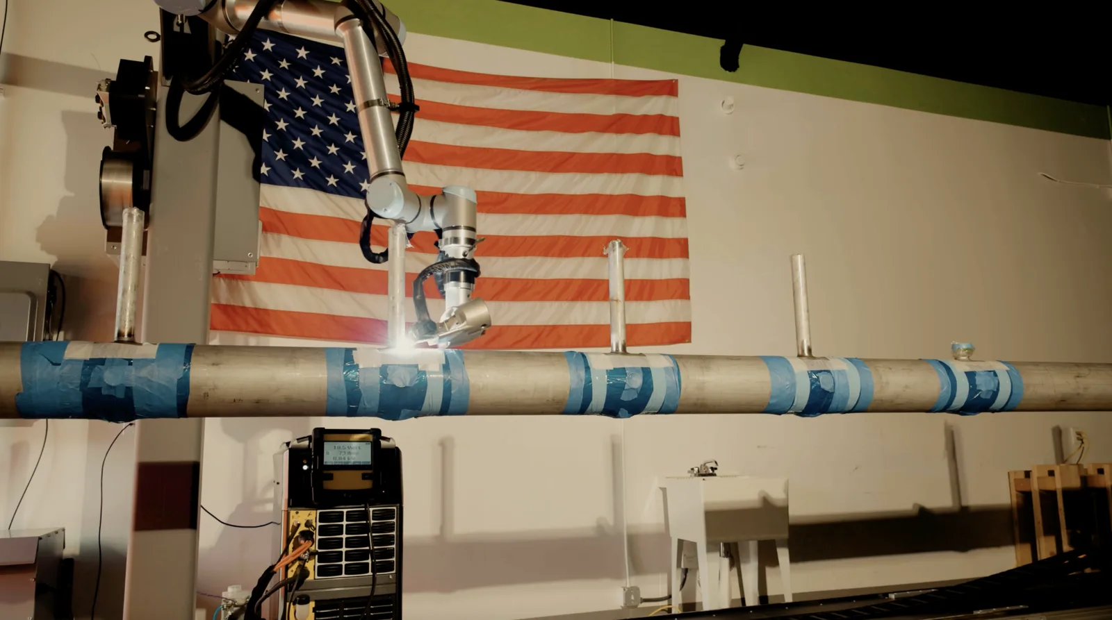 Ten-branch pulled-tee header loaded on the AutonoWeld M4 rail with the cobot torch positioned above