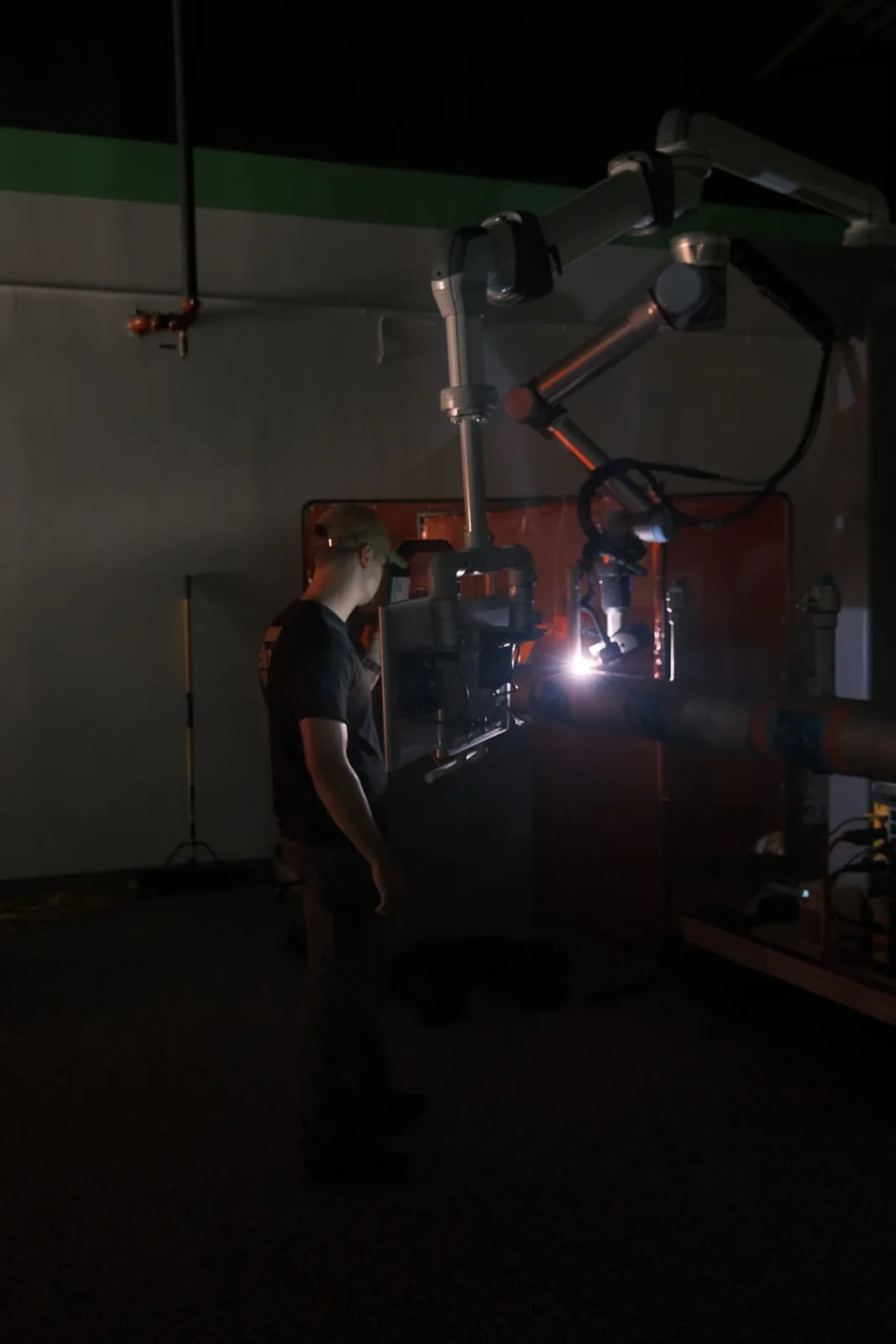Operator watching the AutonoWeld M4 cobot complete a pipe weld inside the welding cell
